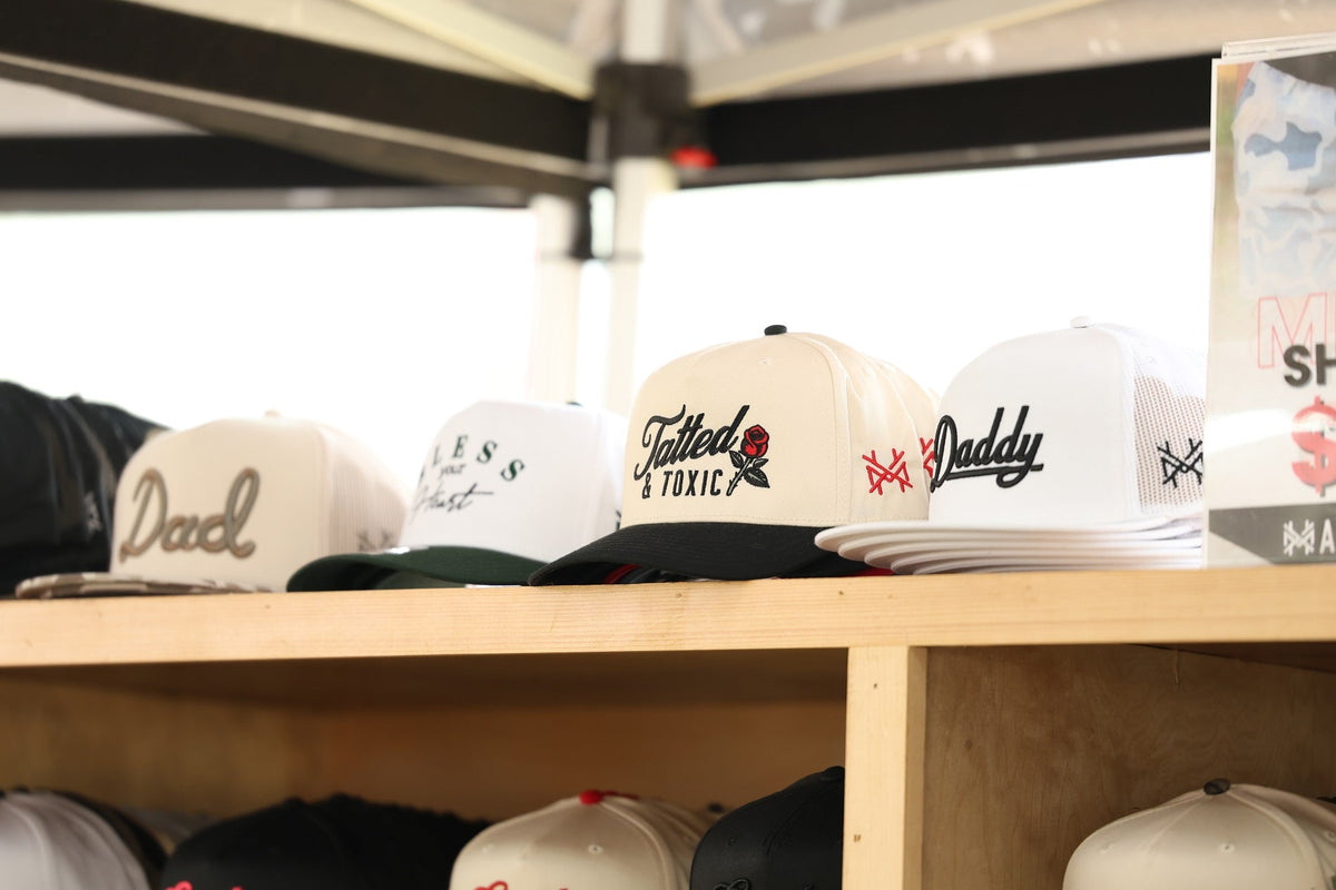 A variety of embroidered hats displayed on wooden shelves.