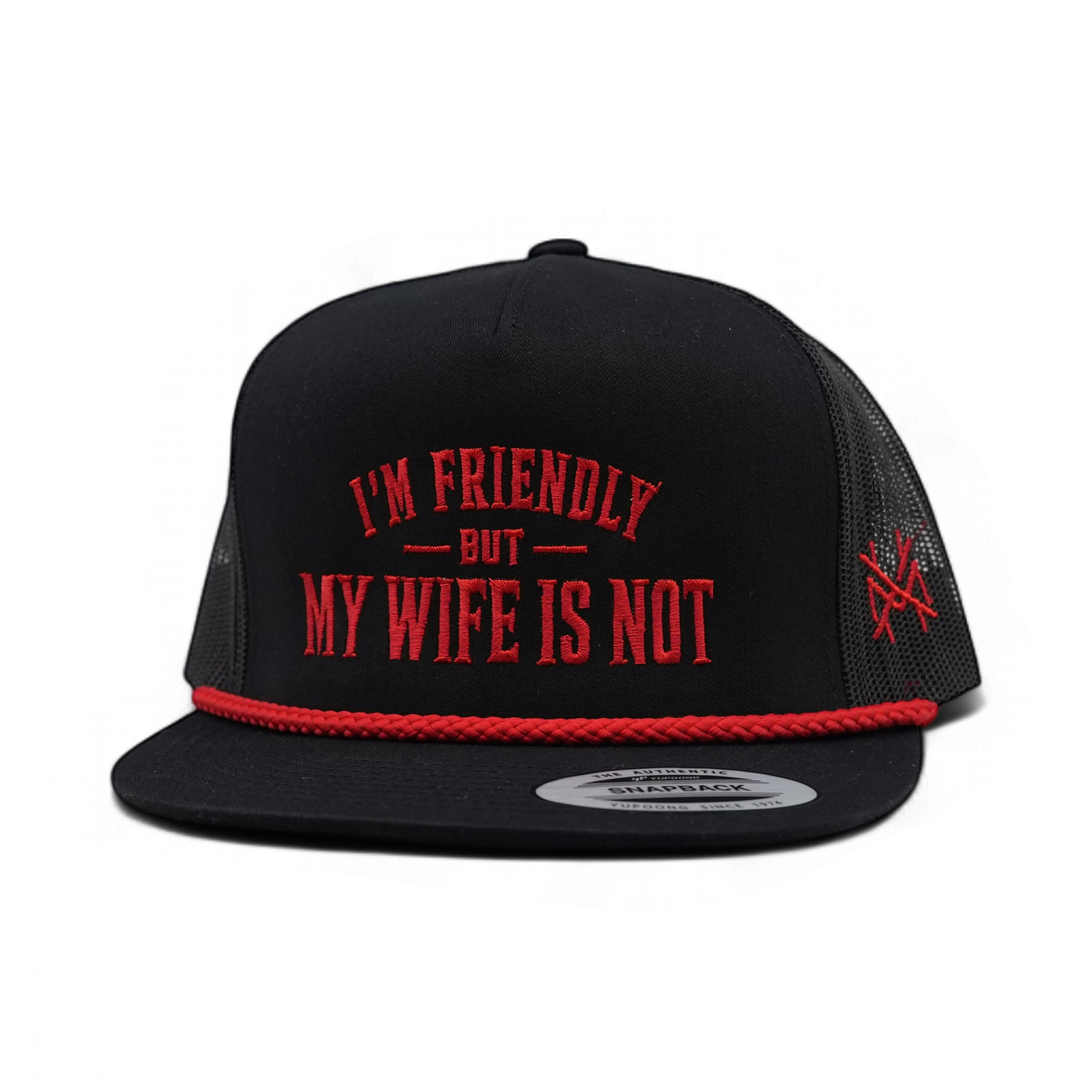 A black trucker-style snapback cap with red embroidered text reading 'I'M FRIENDLY BUT MY WIFE IS NOT' on the front, a red braided trim along the brim, and a red embroidered logo on the side mesh. The cap is photographed on a clean white background.