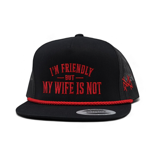 A black trucker-style snapback cap with red embroidered text reading 'I'M FRIENDLY BUT MY WIFE IS NOT' on the front, a red braided trim along the brim, and a red embroidered logo on the side mesh. The cap is photographed on a clean white background.
