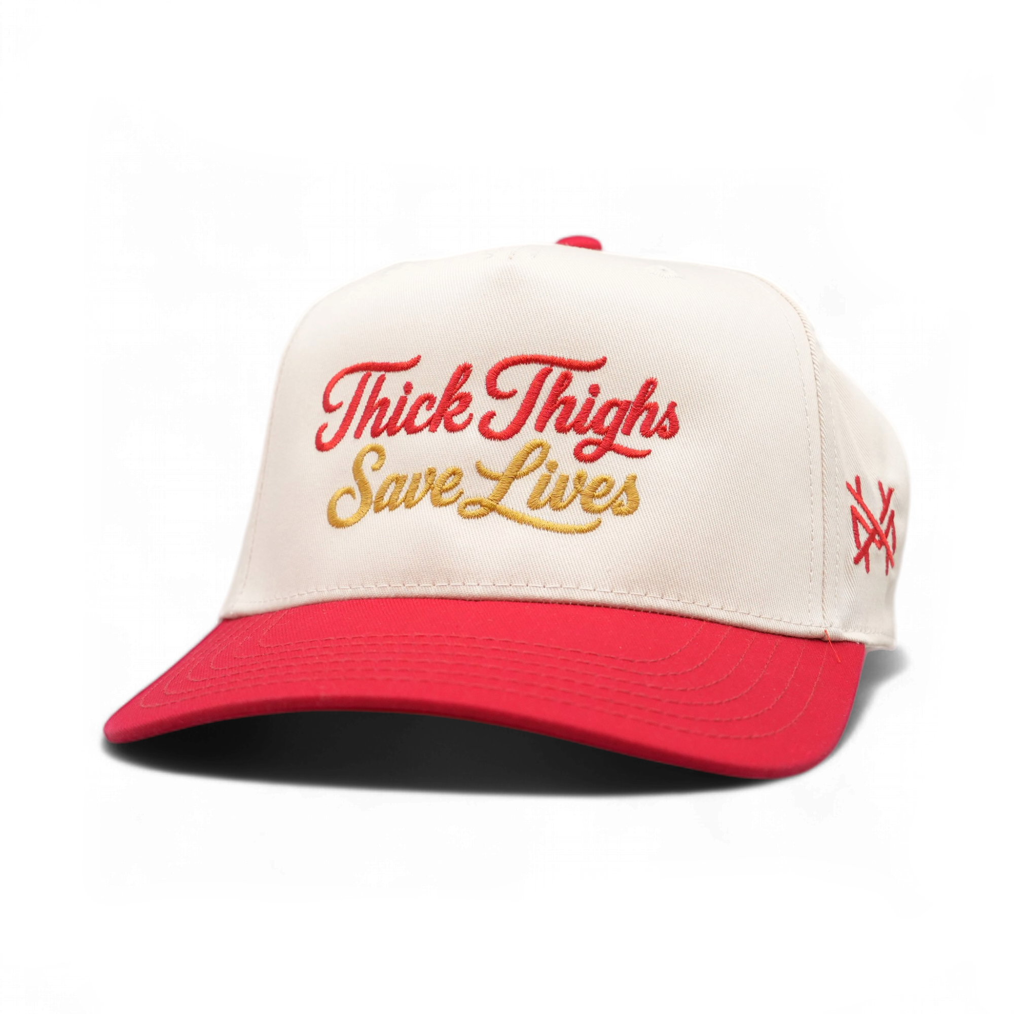 A red and off-white trucker cap with 'Thick Thigs Save Lives' embroidered on the front in red and gold, and a red 'TX' logo on the side, set against a plain white background.