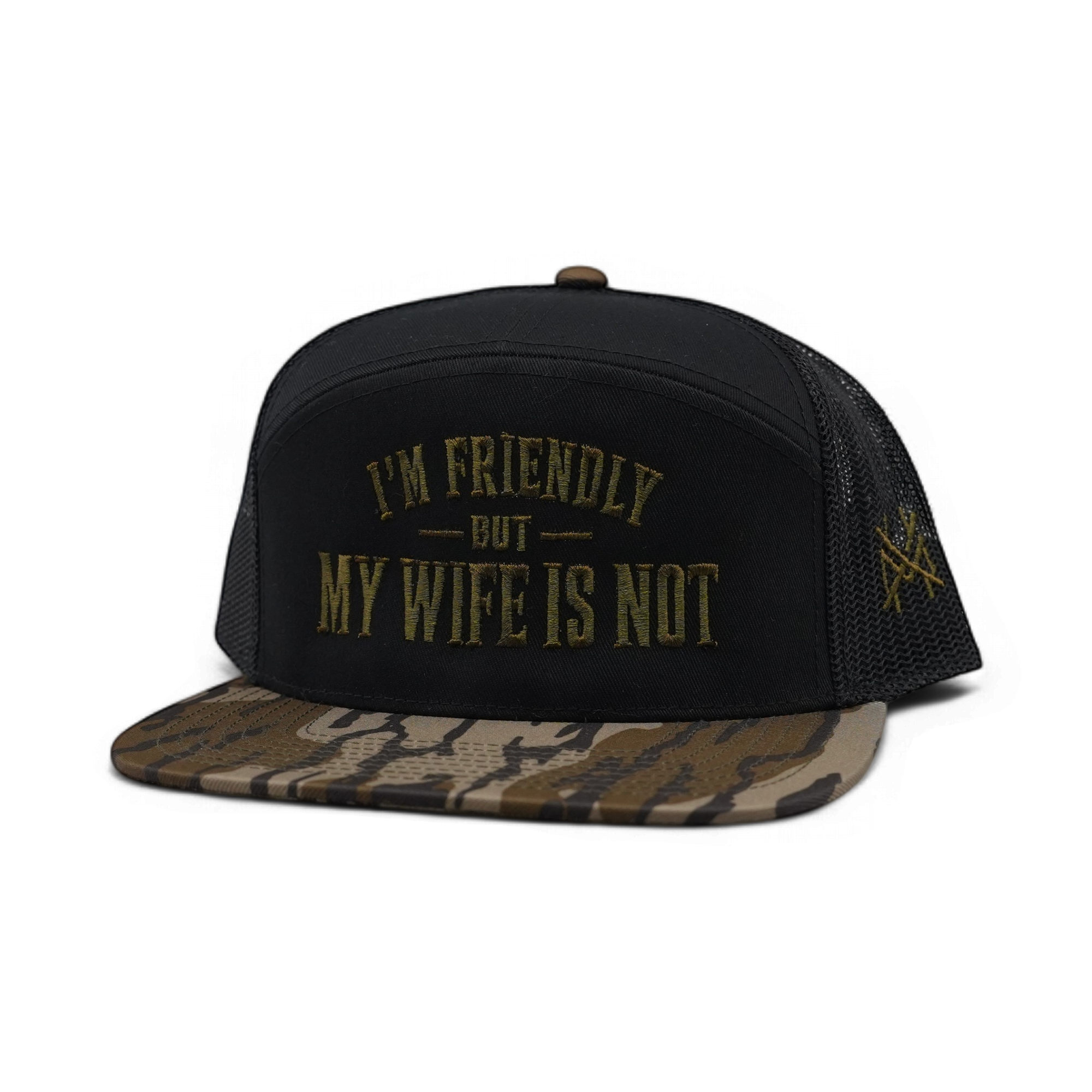 A black trucker-style cap with a camouflage-patterned flat brim, featuring the text 'I'M FRIENDLY BUT MY WIFE IS NOT' embroidered in gold on the front, and a small gold star logo on the side mesh.