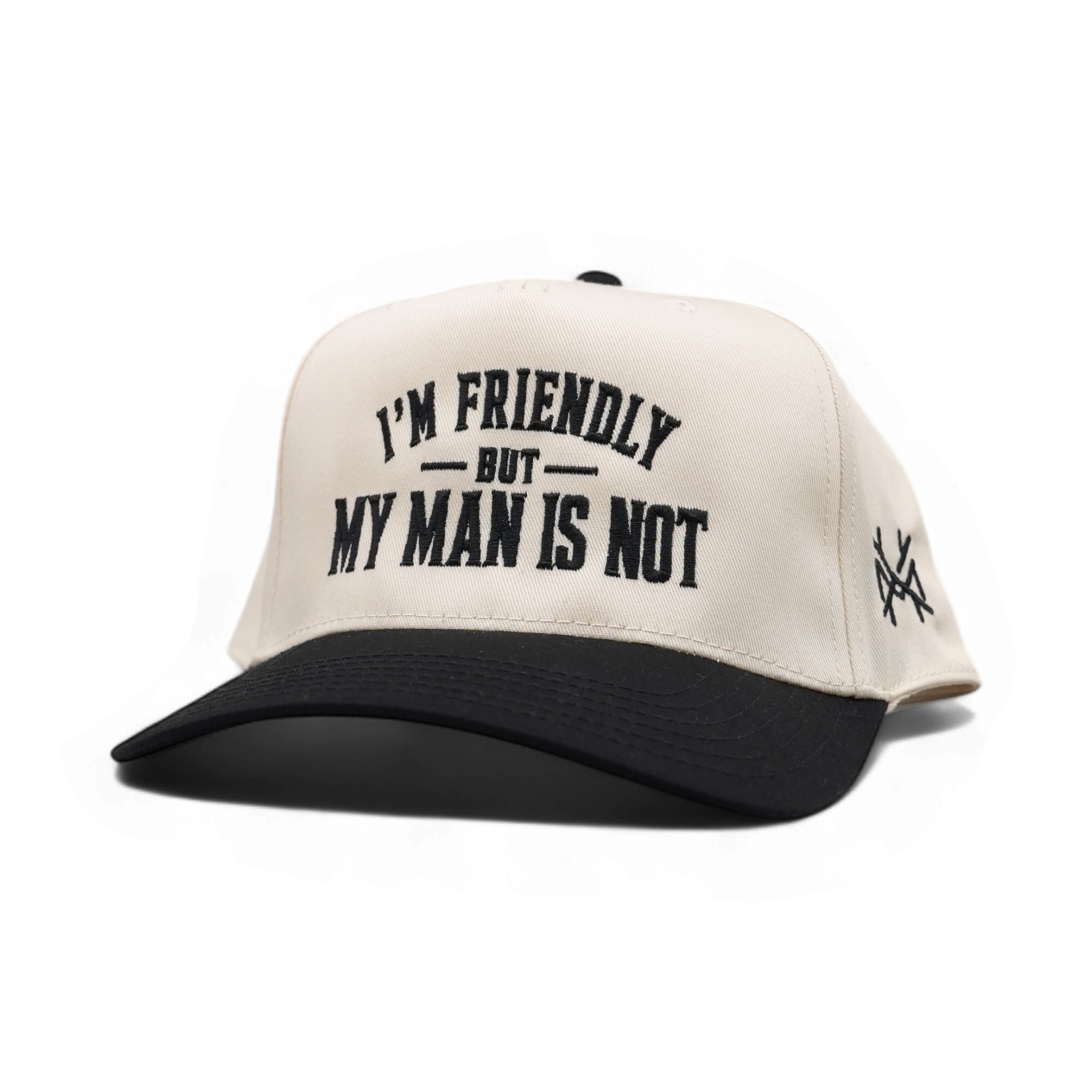 An off-white and black trucker-style cap with the text 'I'M FRIENDLY BUT MY MAN IS NOT' embroidered on the front, and a small black logo on the side, shown on a plain white background.