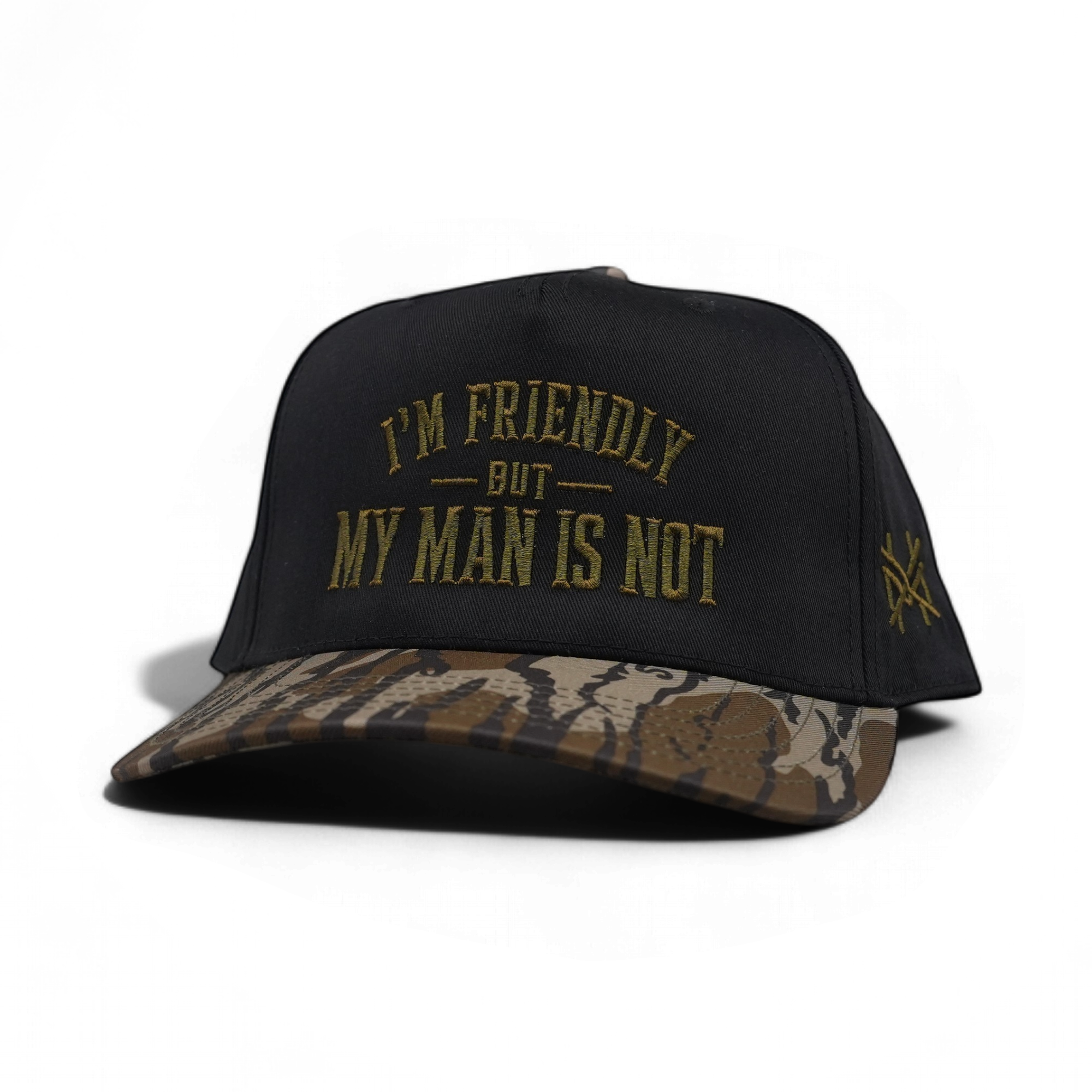 A black snapback cap with a camouflage-patterned visor and gold embroidered text reading 'I'M FRIENDLY BUT MY MAN IS NOT' on the front, shown on a white background.