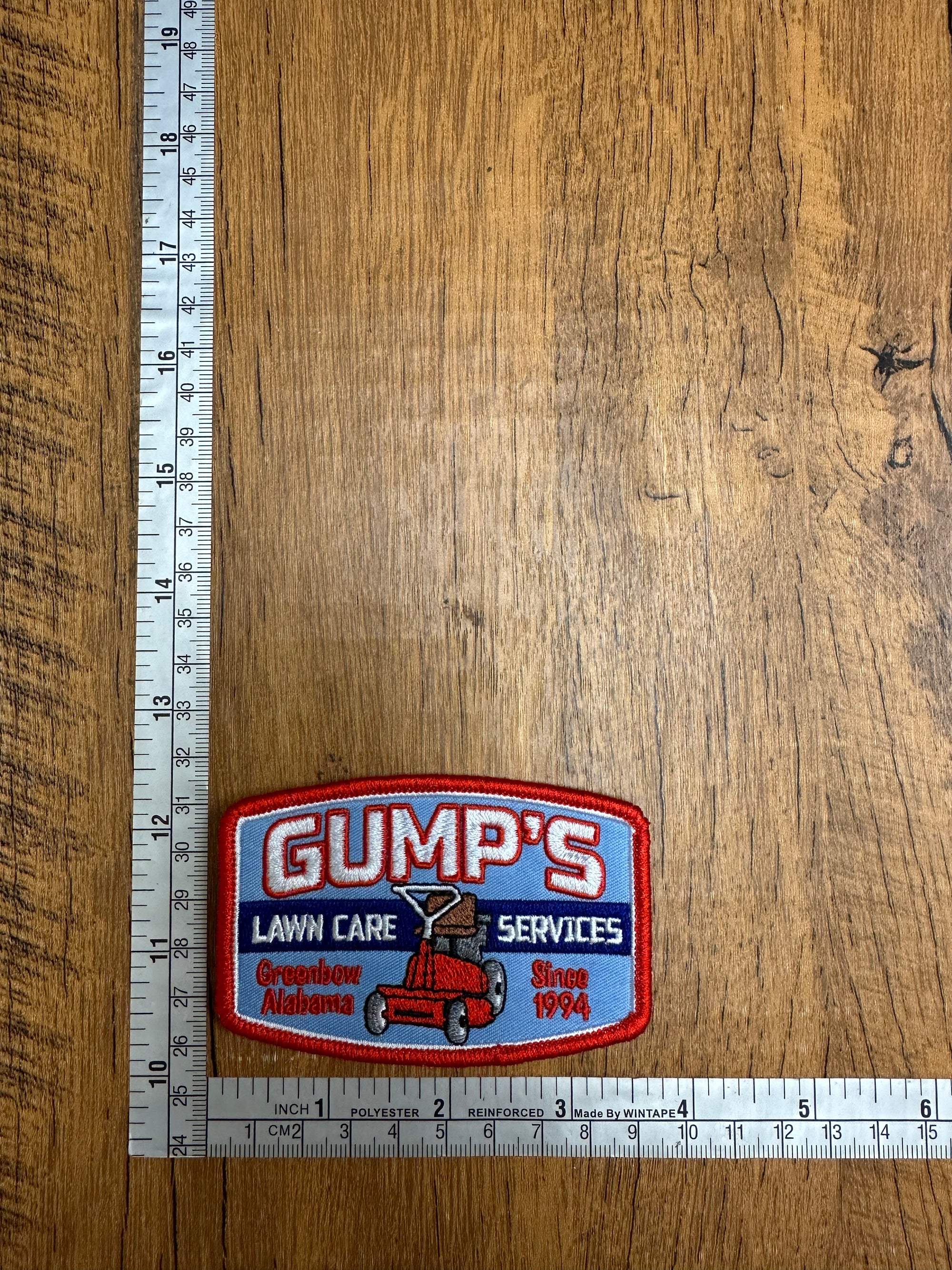 A patch with the Gump's Lawn Care Services logo from The Mad Hatter Company, featuring vibrant colors and detailed design.